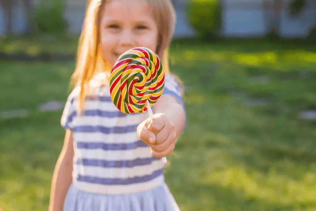 Young girl showing off her colorful lollipop.