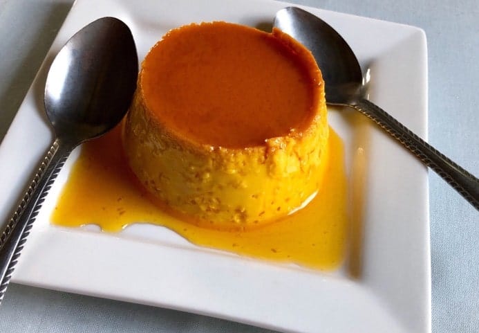 Flan on a plate with two spoons.